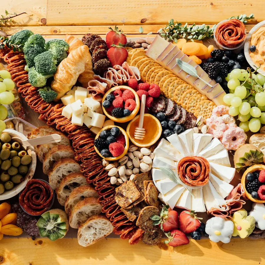 Una tabla de madera con embutidos, quesos, aceitunas y pan vista desde arriba