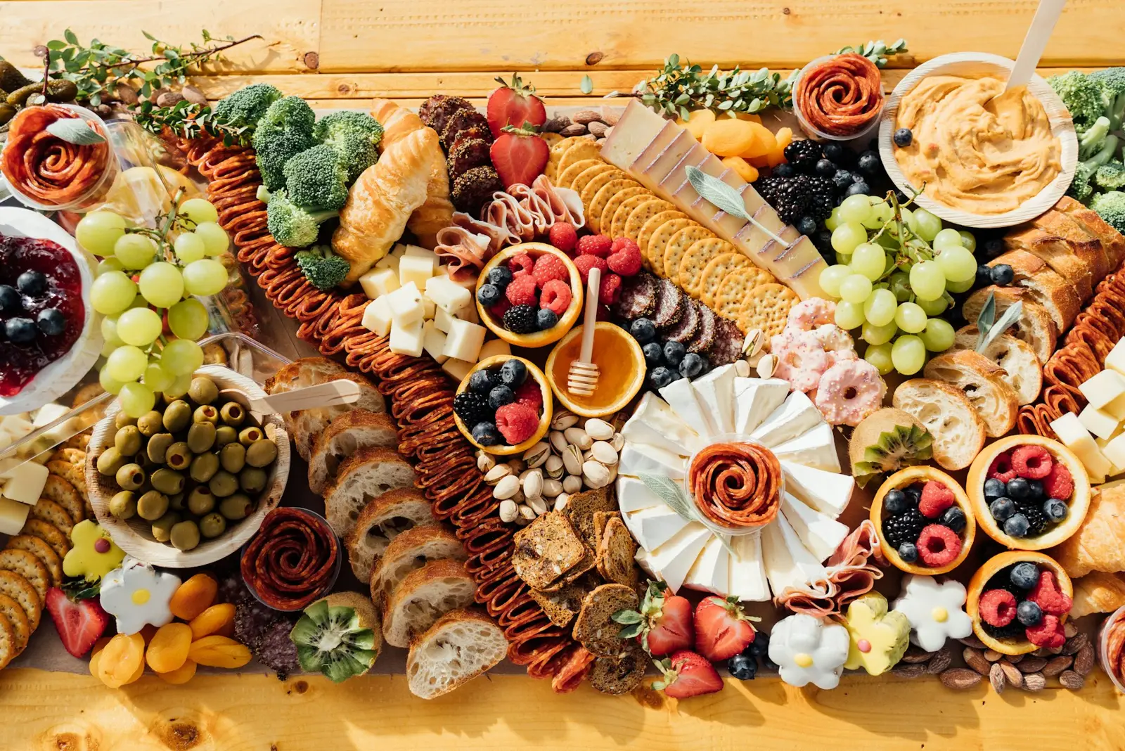 Una tabla de madera con embutidos, quesos, aceitunas y pan vista desde arriba