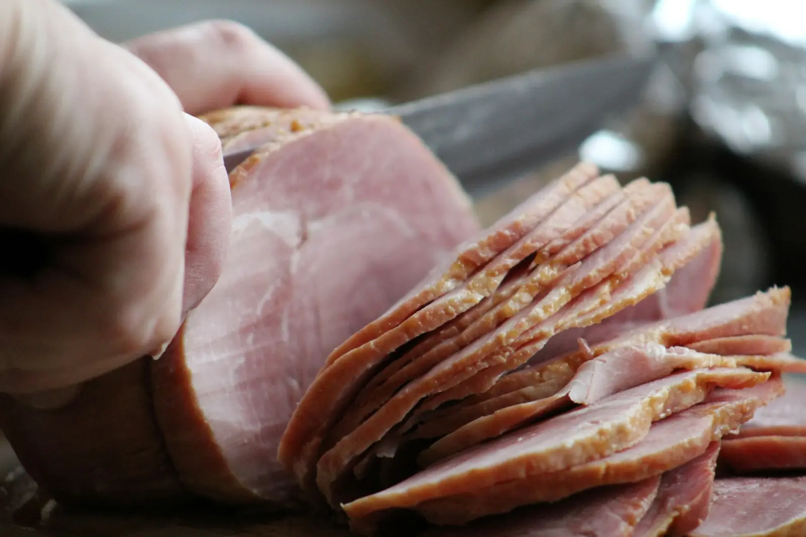Manos cortando jamón con un cuchillo largo